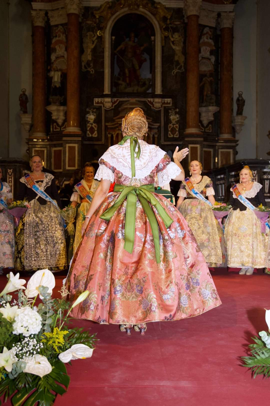 Fallera con traje rosa ante el altar de una iglesia