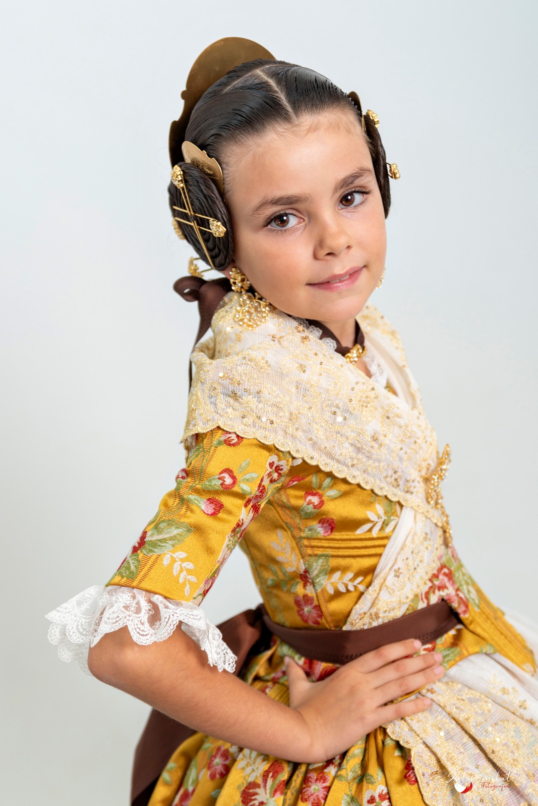 Niña con traje de espolín amarillo de flores y aderezo dorado