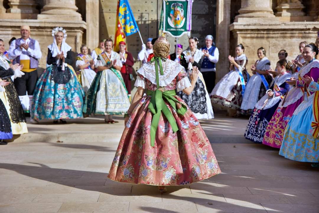 Fallera con traje rosa en una plaza entre aplausos